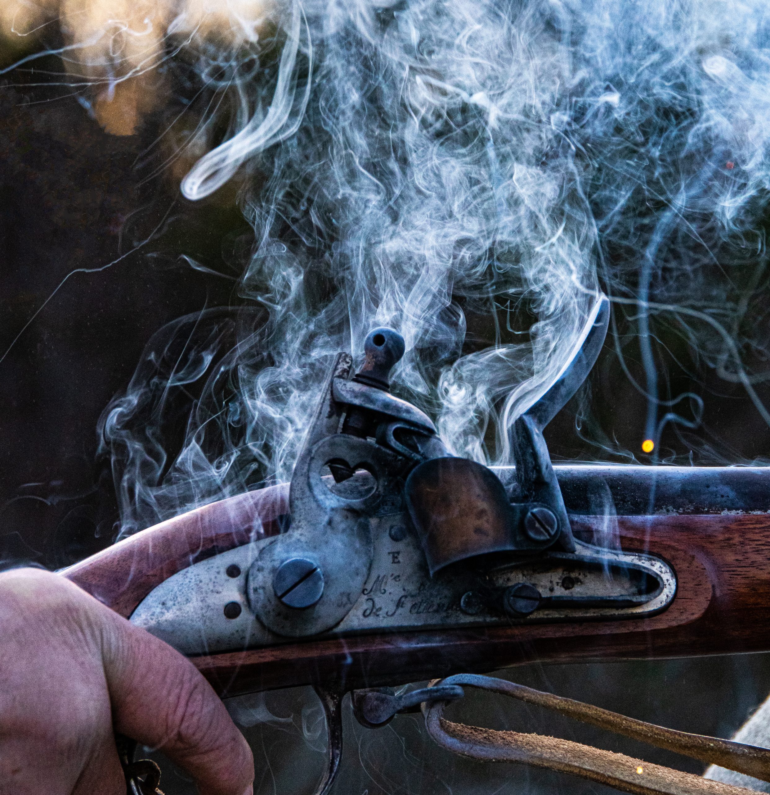 Close-up of a fired flintlock musket from Saint-Étienne with smoke curling from the lock mechanism, showing fine craftsmanship and historical firearm design.